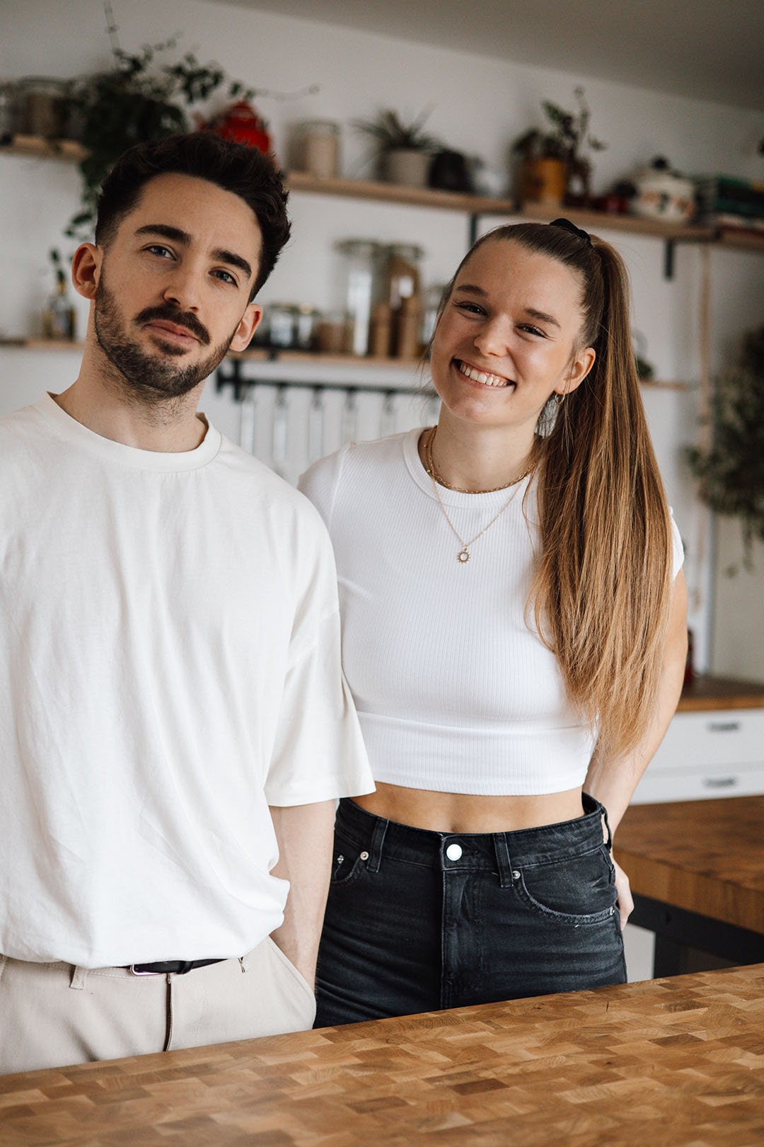 Two people smiling in a kitchen with wooden countertops.