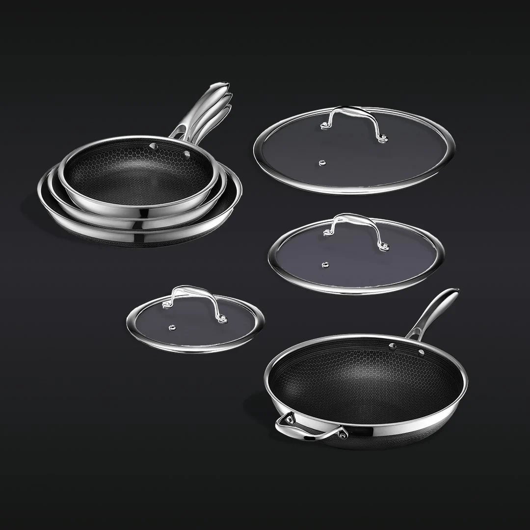 Stacked frying pans and lids on a dark background.